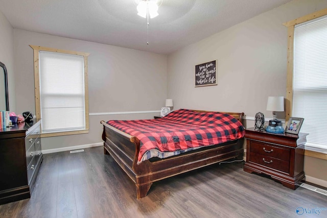 bedroom with a textured ceiling, ceiling fan, and dark wood-type flooring