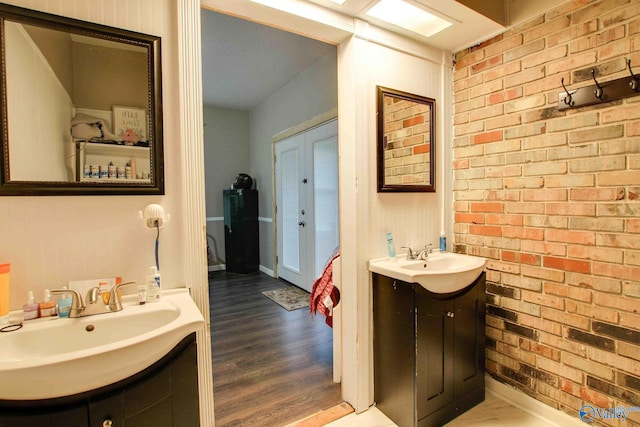 bathroom featuring wood-type flooring, vanity, and brick wall