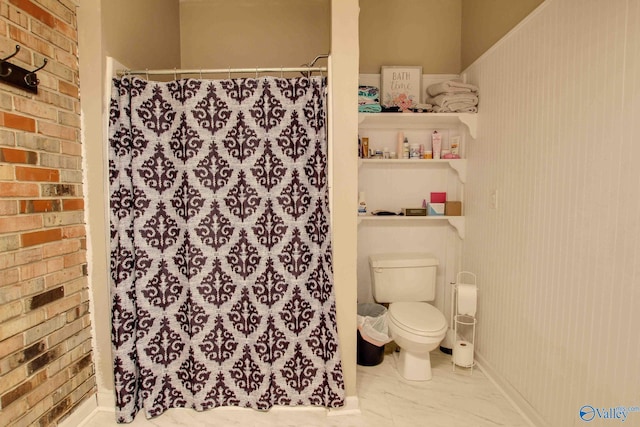 bathroom with toilet, walk in shower, and brick wall