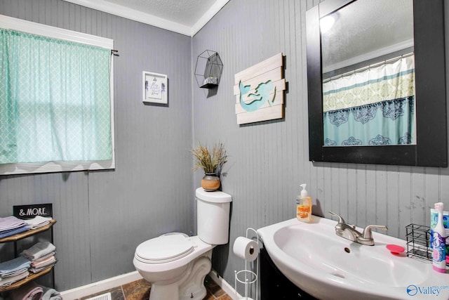 bathroom featuring tile patterned floors, a textured ceiling, crown molding, sink, and toilet