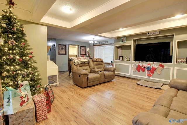 living room with a chandelier, a raised ceiling, and light hardwood / wood-style flooring