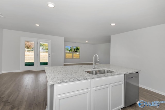 kitchen featuring an island with sink, sink, white cabinets, stainless steel dishwasher, and light stone counters