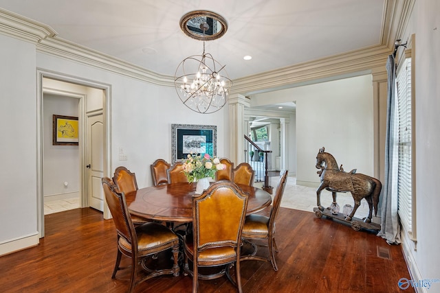 dining room with decorative columns, hardwood / wood-style flooring, crown molding, and a chandelier