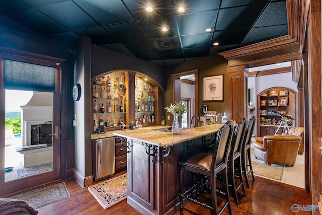 bar with dark hardwood / wood-style flooring, light stone countertops, refrigerator, and built in shelves