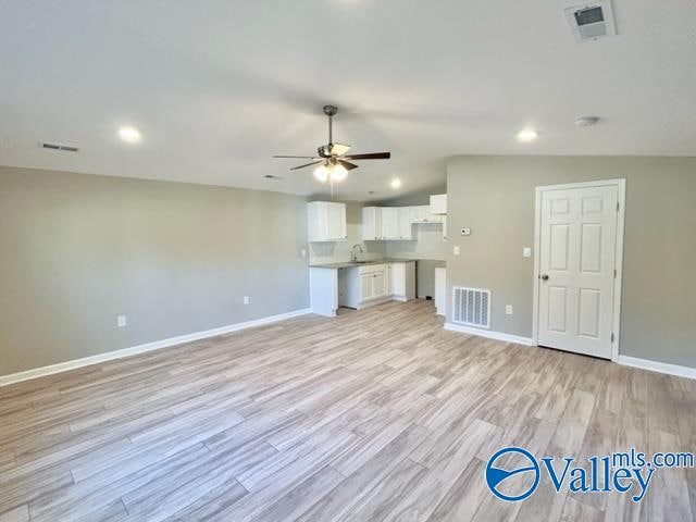 unfurnished living room with lofted ceiling, sink, light hardwood / wood-style floors, and ceiling fan