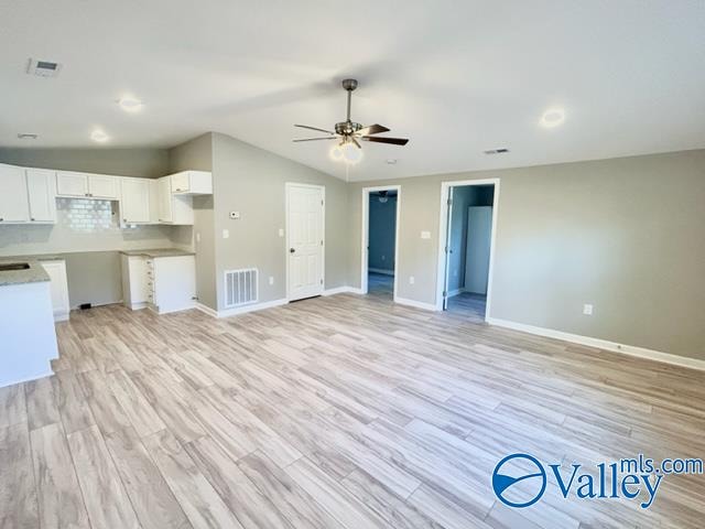 unfurnished living room with vaulted ceiling, light hardwood / wood-style flooring, and ceiling fan