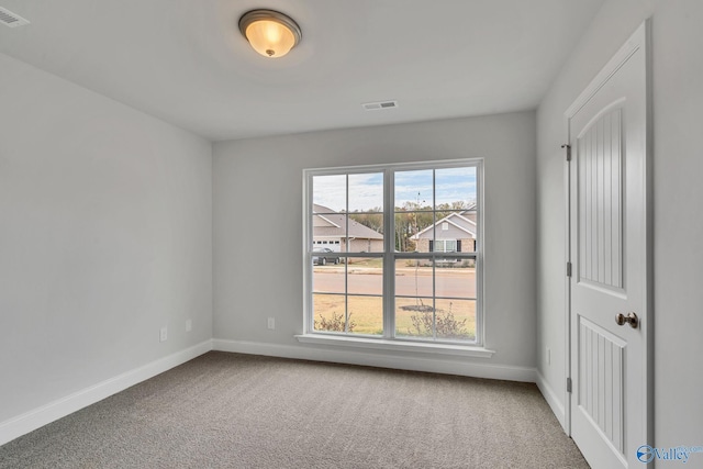 empty room featuring visible vents, carpet floors, and baseboards