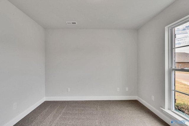 spare room featuring carpet flooring, baseboards, and visible vents