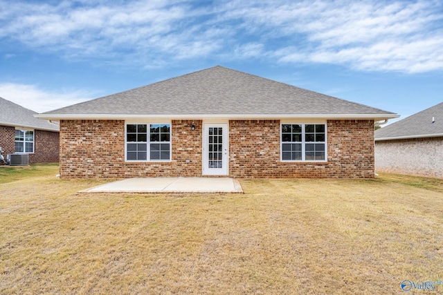 rear view of property with central AC, roof with shingles, a lawn, and a patio area