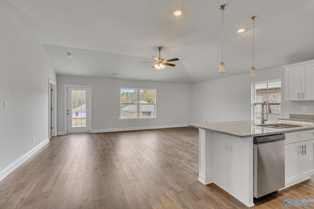 kitchen featuring light stone counters, pendant lighting, a sink, dishwasher, and a ceiling fan