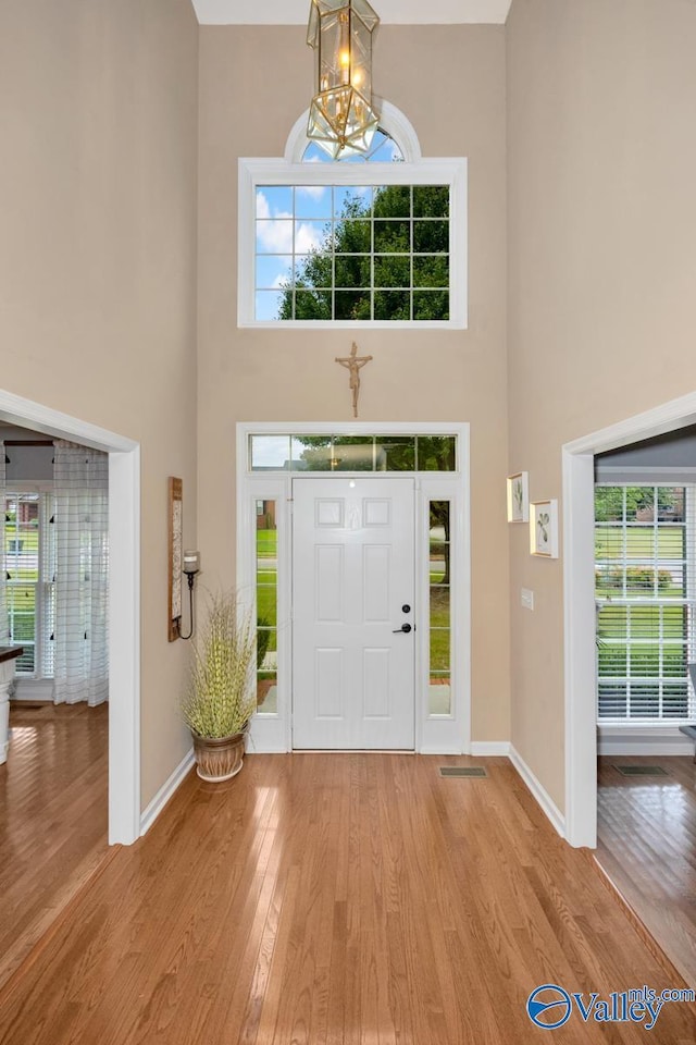 entryway with a high ceiling, a notable chandelier, and light wood-type flooring