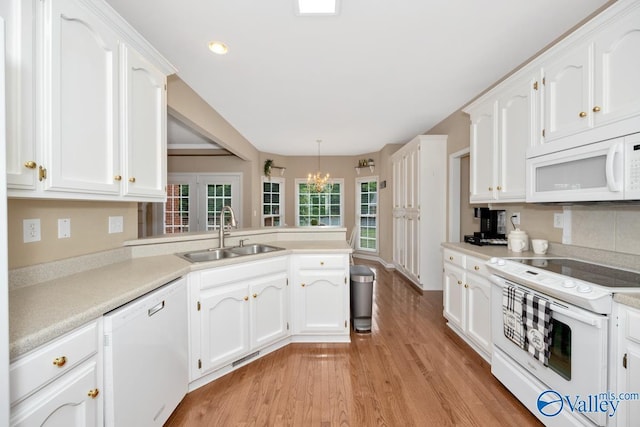 kitchen with white cabinetry, white appliances, kitchen peninsula, and sink