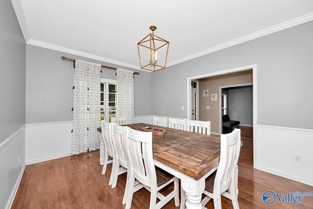 dining space featuring an inviting chandelier, hardwood / wood-style flooring, and ornamental molding