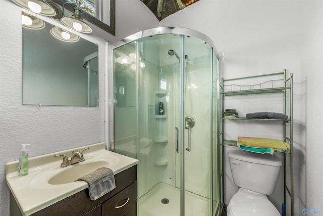 bathroom with walk in shower, vanity, and toilet