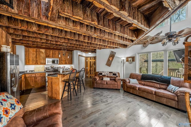 living room featuring dark wood-type flooring, ceiling fan, and a high ceiling