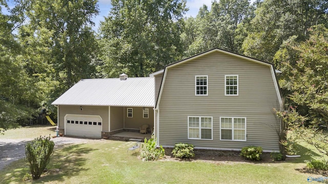 view of front of property featuring a gambrel roof, a front yard, metal roof, driveway, and an attached garage