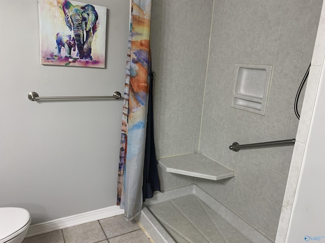 bathroom featuring a tile shower, tile patterned floors, and toilet