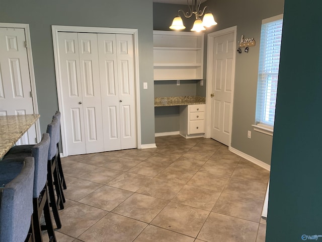 interior space featuring tile patterned flooring, a notable chandelier, and built in shelves