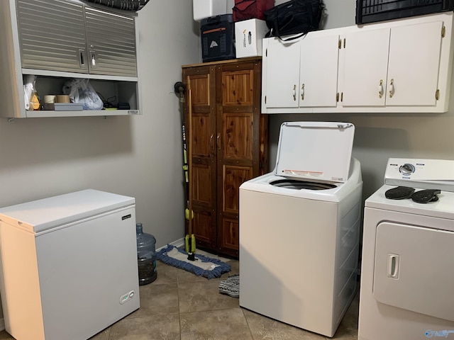 laundry room featuring independent washer and dryer, cabinets, and light tile patterned floors