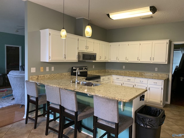 kitchen featuring appliances with stainless steel finishes, sink, white cabinets, hanging light fixtures, and kitchen peninsula