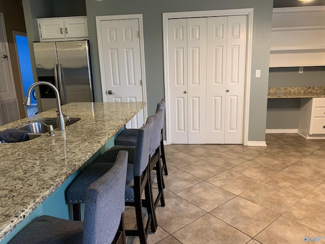 kitchen with a breakfast bar, sink, white cabinetry, high end refrigerator, and built in desk