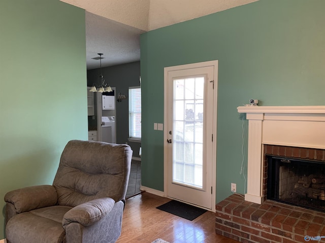 entryway with washer / dryer, hardwood / wood-style floors, a textured ceiling, and a brick fireplace