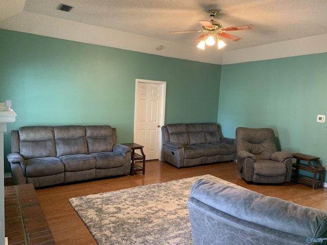 living room featuring ceiling fan, hardwood / wood-style floors, and a textured ceiling