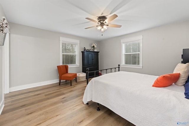 bedroom featuring a ceiling fan, baseboards, multiple windows, and light wood finished floors