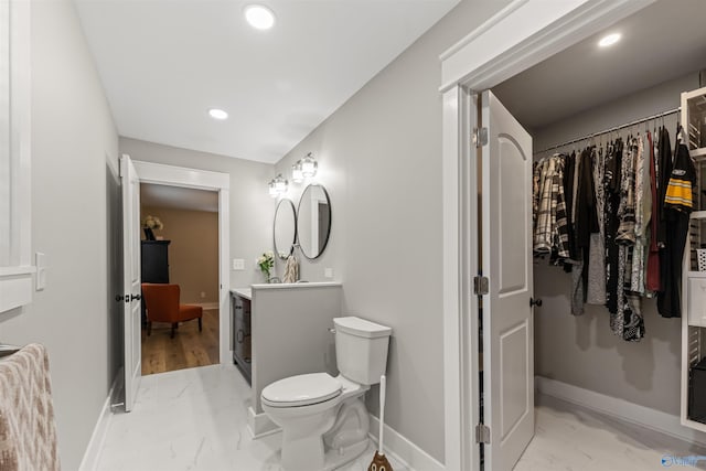 bathroom with marble finish floor, a spacious closet, baseboards, and vanity