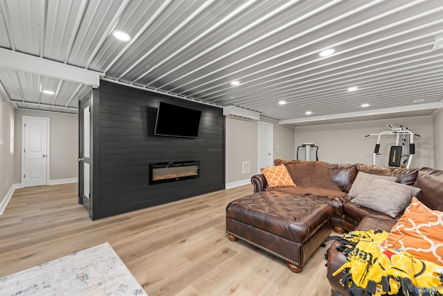 living room featuring a fireplace, visible vents, baseboards, a wall mounted AC, and light wood finished floors