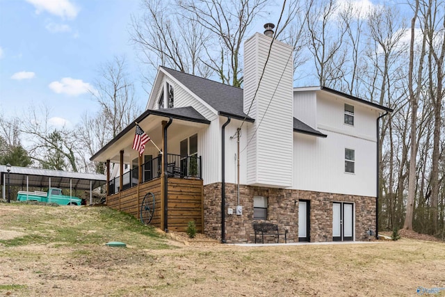 view of side of home with stone siding, roof with shingles, a yard, and a chimney