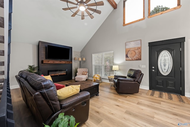 living room with a large fireplace, baseboards, plenty of natural light, and light wood finished floors