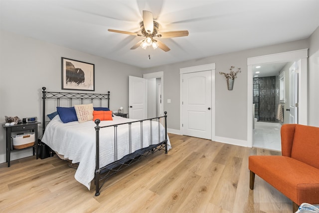 bedroom featuring light wood-style floors, ceiling fan, ensuite bath, and baseboards