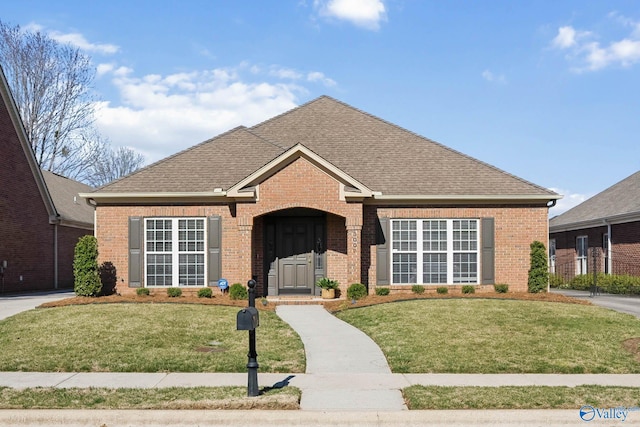 ranch-style house featuring a front yard, brick siding, and roof with shingles