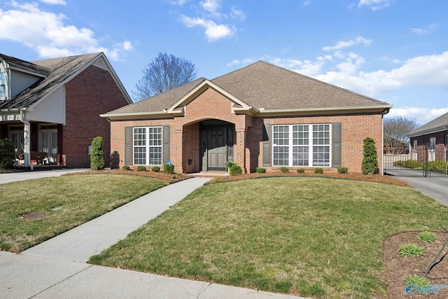 ranch-style home featuring brick siding, roof with shingles, and a front yard