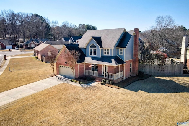 traditional home with concrete driveway, a porch, fence, a front lawn, and brick siding