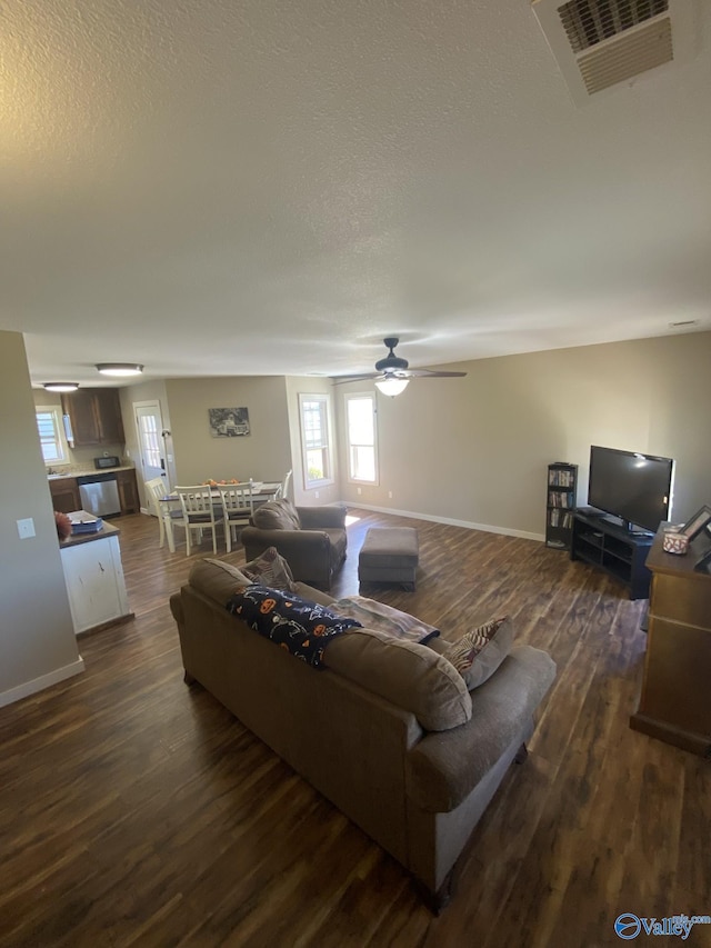 living room with ceiling fan, dark hardwood / wood-style flooring, and a textured ceiling