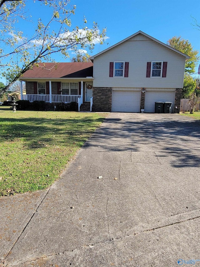 tri-level home with covered porch, a garage, and a front yard