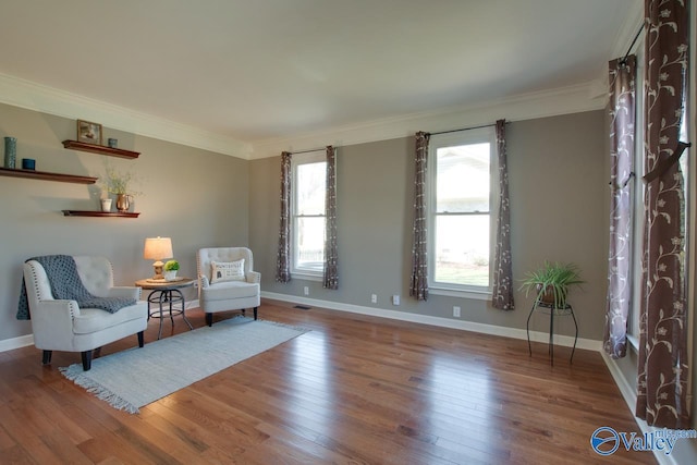 sitting room with baseboards, crown molding, and wood finished floors