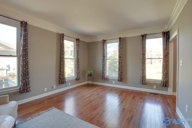 interior space featuring ornamental molding, visible vents, baseboards, and hardwood / wood-style flooring