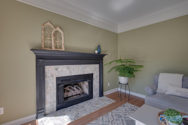 living area with baseboards, a fireplace with flush hearth, ornamental molding, and wood finished floors