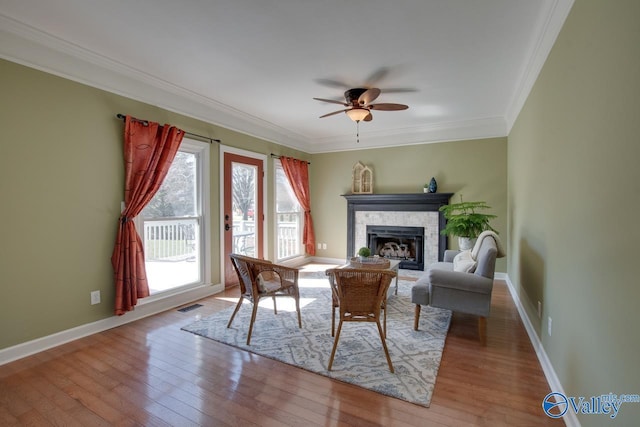 living room with a fireplace, visible vents, hardwood / wood-style floors, ornamental molding, and baseboards