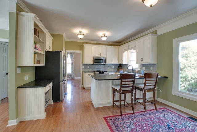 kitchen with stainless steel appliances, a peninsula, light wood-type flooring, open shelves, and dark countertops