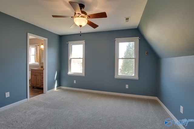 unfurnished bedroom featuring carpet floors, lofted ceiling, visible vents, connected bathroom, and baseboards