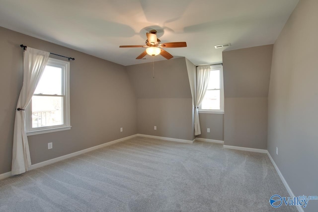 empty room featuring light carpet, baseboards, visible vents, a ceiling fan, and lofted ceiling