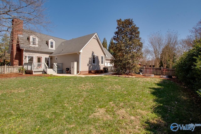 rear view of house with fence and a yard