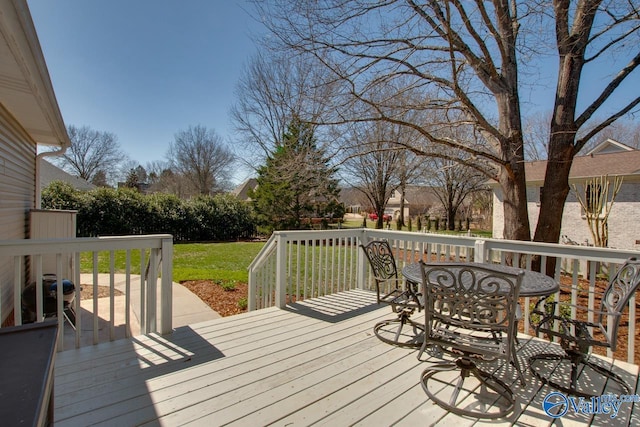 wooden deck featuring outdoor dining space and a lawn