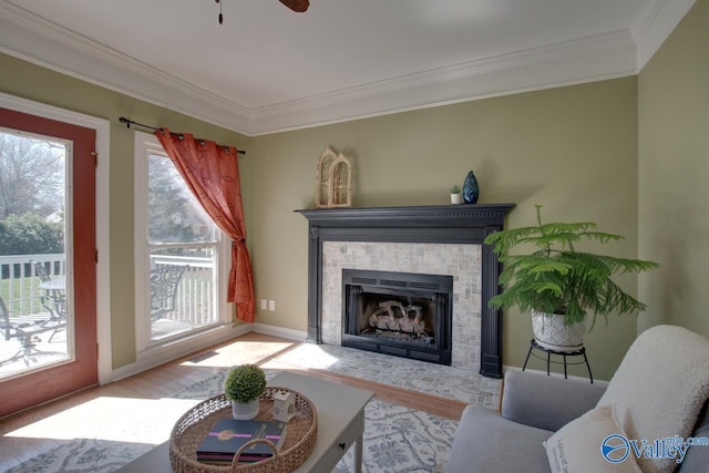 living area featuring a brick fireplace, ornamental molding, and wood finished floors