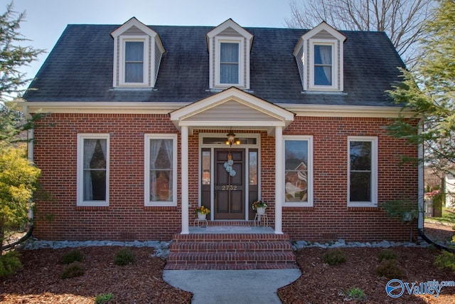 cape cod house with roof with shingles and brick siding