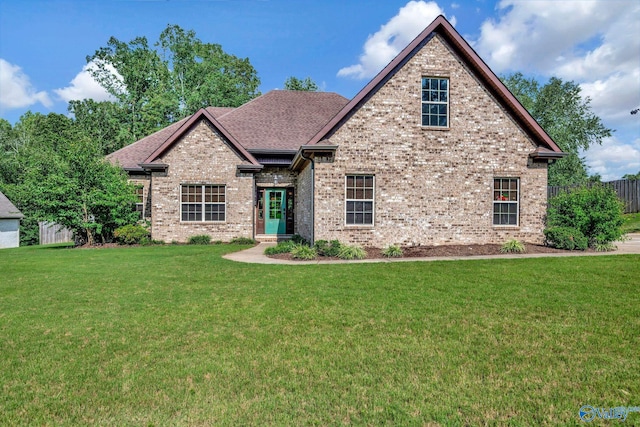 view of front of property with a shingled roof, a front yard, brick siding, and fence